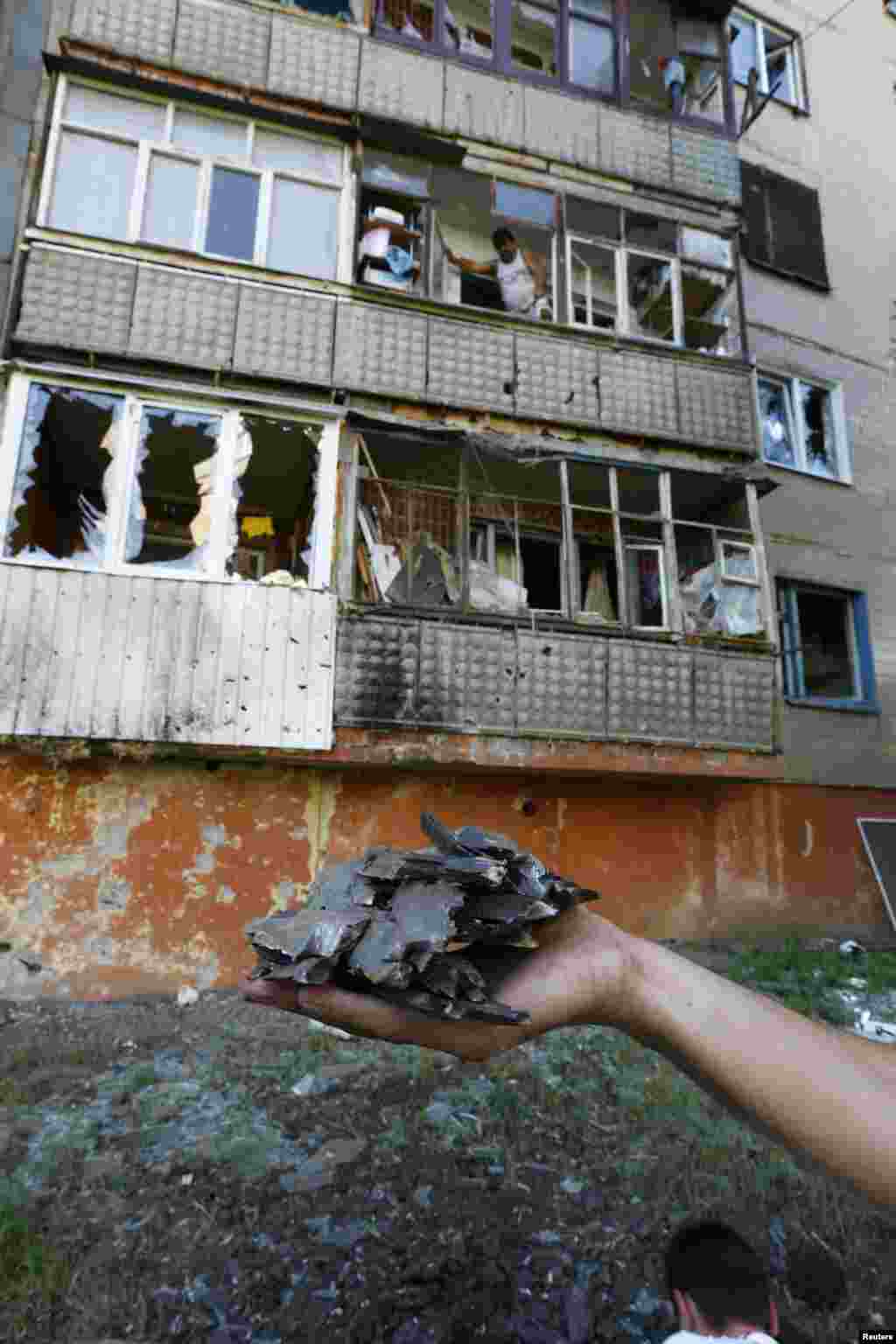 A local resident holds fragments of shrapnel near an apartment damaged by shelling in Slovyansk, June 29, 2014.