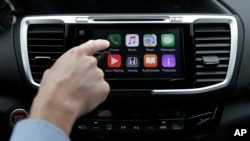 FILE - Chris Martin from Honda North America demonstrates Apple CarPlay, which lets drivers use an iPhone and its voice-activated assistant, Siri, to operate some of their vehicle’s electronic controls and entertainment systems, in Torrance, Calif., August 20, 2015.