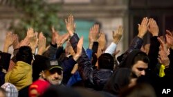 Orang-orang mengangkat tangan dan meneriakkan slogan di Bucharest, Rumania, dalam sebuah protea kepada pemerintah menuntut pemerintahan yang lebih baik dan mengakhiri korupsi, 7 November 2015. 