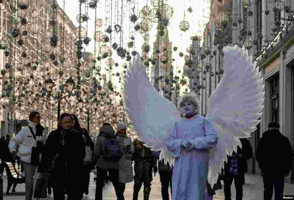 A man dressed as an angel stands on a street in Moscow, Russia.