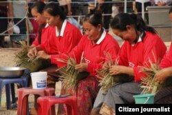 ກຸ່ມແມ່ຍິງ ລາວ ສະແດງທິດສະດີໃນການສານກະຕ່າໄມ້ໄຜ່ ໃນງານວາງສະແດງສິນຄ້າແຫ່ງໜຶ່ງ.