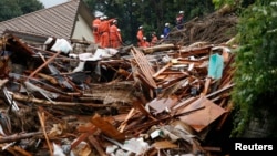 日本消防人員在廣島安佐南區冒雨搜尋生還者。 8月22日發生的山體滑坡沖毀了這個住宅區。
