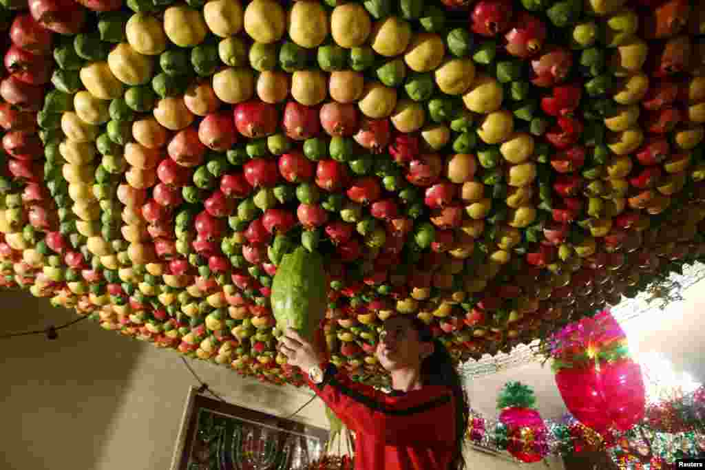 A member of the Samaritan sect decorates a traditional hut known as a sukkah with fruits and vegetables on Mount Gerizim, on the outskirts of the West Bank city of Nablus.&nbsp;