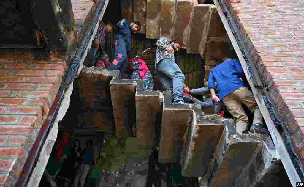 Kashmiri villagers look inside a damaged house following a gunfight between militants and Indian government forces at Panjran village in Pulwama, south of Srinagar.