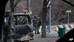 FILE - Soldiers are seen though a bus, which was burned during clashes, as they patrol a street near the central square blocked by Kazakhstan troops and police in Almaty, Kazakhstan, Jan. 10, 2022. 