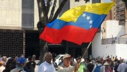 Hombre sostiene una bandera de Venezuela en una protestas de jubilados del país para exigir, de nuevo, pensiones dignas. Foto: Álvaro Algarra -VOA.