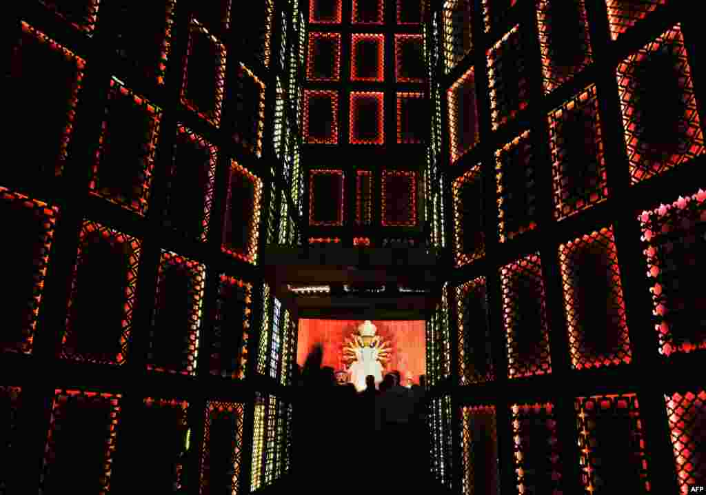 Indian Hindu devotees gather in front of a puja pandal, an area to worship the Hindu Goddess Durga ahead of the forthcoming Durga Puja festival in Kolkata. 