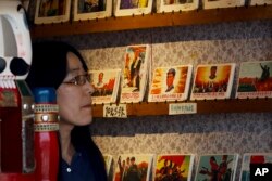 A woman walks past a rack displaying the cards depicting former Chinese leader Mao Zedong and the great army of the Cultural Revolution for sale at a souvenir shop in Beijing, May 17, 2016.