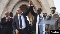 France's President Francois Hollande (2nd L) joins hands with Mali's interim president Dioncounda Traore at Independence Plaza in Bamako, Mali February 2, 2013.