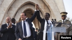 France's President Francois Hollande (2nd L) joins hands with Mali's interim president Dioncounda Traore at Independence Plaza in Bamako, Mali February 2, 2013.