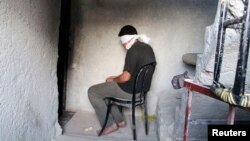 FILE - A blindfolded man waits to be interrogated in a prison in Aleppo, Syria, Oct. 6, 2014. Activists say more than 110,000 detainees are currently being held in Syria, most of them by the government of President Bashar al-Assad.