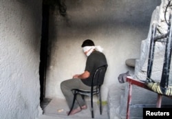 FILE - A blindfolded man waits to be interrogated in a prison in Aleppo, Syria, Oct. 6, 2014. Activists say more than 110,000 detainees are currently being held in Syria, most of them by the government of President Bashar al-Assad.