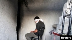 A blindfolded man waits to be interrogated in a prison in Aleppo, Syria. (File)