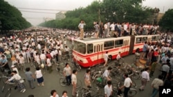 资料照：大批人群在北京一处交叉路口试图用公共汽车和路障拦阻军队向天安门广场推进。(1989年6月3日)