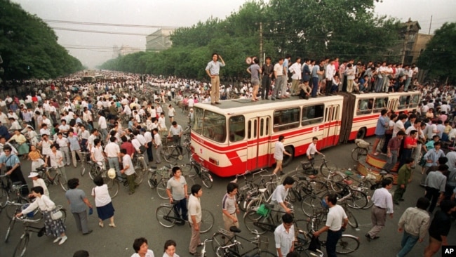 资料照：大批人群在北京一处交叉路口试图用公共汽车和路障拦阻军队向天安门广场推进。(1989年6月3日)