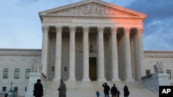 People stand on the plaza in front of the Supreme Court at sunset, Feb. 13, 2016, in Washington. 