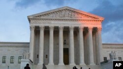FILE - People stand on the plaza in front of the Supreme Court at sunset, Feb. 13, 2016, in Washington.