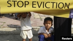 A Cambodian girl holds a banner next to a boy as former residents of the Dey Krahorm community gather in front of the site where they used to live before being evicted by government forces in Phnom Penh January 24, 2012. 