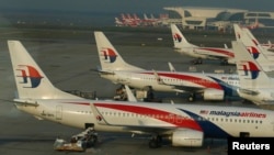 Ground crew work among Malaysia Airlines planes on the runway at Kuala Lumpur International Airport (KLIA) in Sepang, July 25, 2014. 