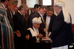 Afghan President Ashraf Ghani, center, signs a peace agreement with Gulbuddin Hekmatyar, a notorious warlord on terrorist blacklists, at the presidential palace in Kabul, Sept. 29, 2016.
