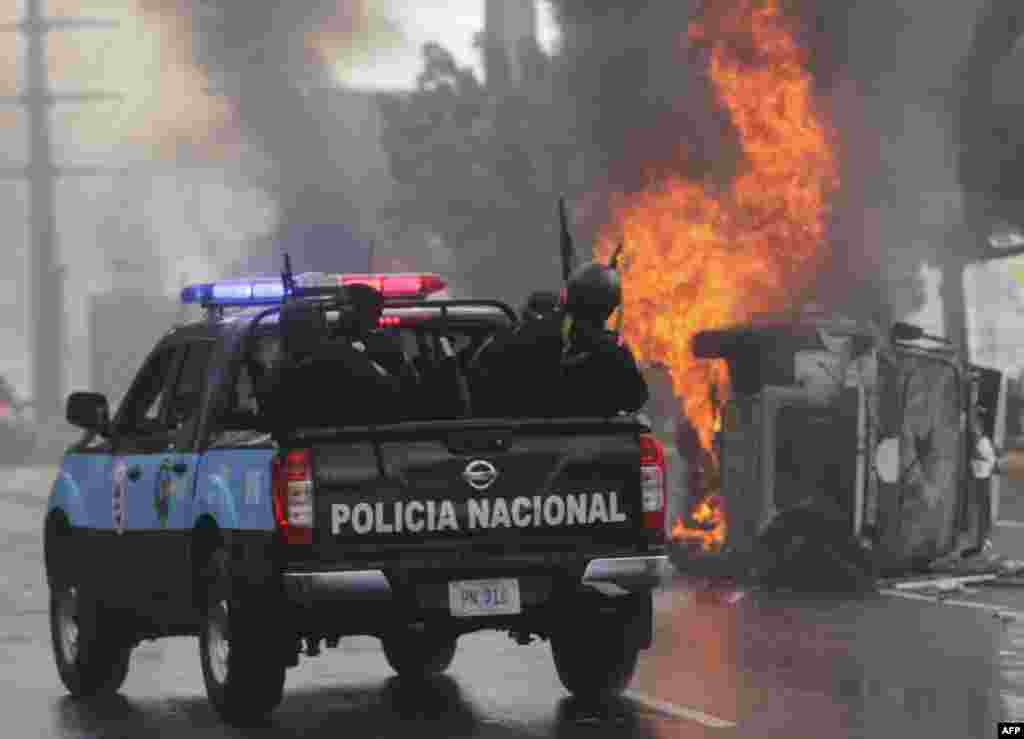 National Police officers in riot gear, drive near an overturned burning police vehicle, after an anti-government protest in Managua, Nicaragua, Sept. 2, 2018.