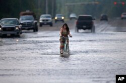 Cara Crawford, turns around after trying to ride her bike through high water to get to Sunday services at a nearby church, in the aftermath of Tropical Storm Harvey in Vidor, Texas, Sept. 3, 2017.