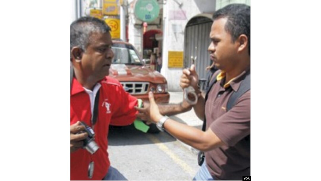 Seorang polisi berpakaian preman mencoba memborgol seorang aktivits (kiri) pada aksi protes Hari Buruh, 1 Mei lalu di Kuala Lumpur.