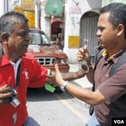 Seorang polisi berpakaian preman mencoba memborgol seorang aktivits (kiri) pada aksi protes Hari Buruh, 1 Mei lalu di Kuala Lumpur.