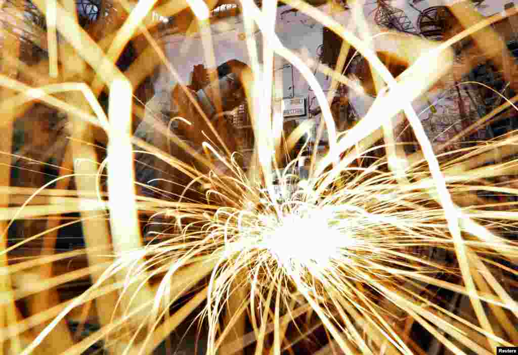 A worker grinds an iron window frame used in a dairy machine at a manufacturing unit in the western Indian city of Ahmedabad. 