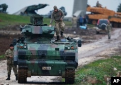 FILE - Turkish soldiers on an armored personnel carrier secure a staging area for troops preparing their tanks to enter combat and join a military offensive on a Kurdish-held enclave in northern Syria, in Hatay province, Turkey, near the the border with Syria, Jan. 23, 2018.