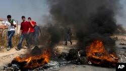 Palestinian protesters burn tires and clash with Israeli army soldiers after troops searched and measured the family house of Omar al-Abed, 20, identified by the Israeli army as the assailant in an attack at the Israeli settlement of Halamish, in preparation for demolition, in the West Bank village of Kobar, near Ramallah, July 22, 2017.