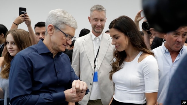 Apple CEO Tim Cook, left and soccer player Alex Morgan discuss the new Apple Watch 4 at the Steve Jobs Theater during an event to announce new products Wednesday, Sept. 12, 2018, in Cupertino, Calif. (AP Photo/Marcio Jose Sanchez)