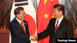 Presiden Korea Selatan Moon Jae-in (kiri) berjabat tangan dengan Presiden China Xi Jinping saat bertemu di KTT APEC, Vietnam, 11 November 2017 (Foto: dok). 