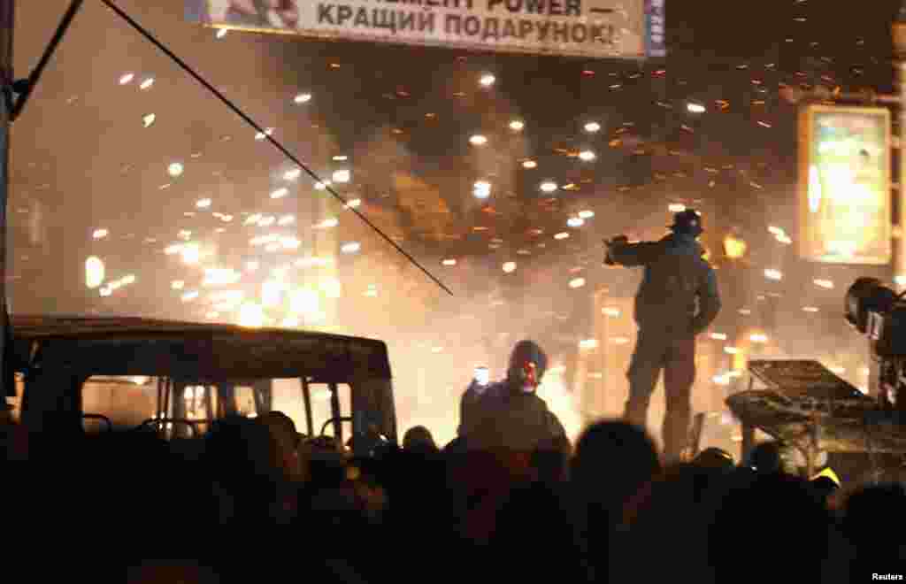 Uma manifestante do movimento pró-Europeu tira uma foto aos confrontos com a polícia de choque, Kiev, Jan. 20, 2014.