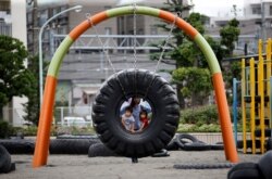 FILE - Children ride on a swing made with an old tire at Nishi Rokugo Park, also known as the Tire Park, at Ota-Ku, in Tokyo, Japan August 17, 2017. The park was built with the concept of recycling by using thousands of old tires. (REUTERS/Kim Kyung-Hoon)