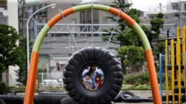FILE - Children ride on a swing made with an old tire at Nishi Rokugo Park, also known as the Tire Park, at Ota-Ku, in Tokyo, Japan August 17, 2017. The park was built with the concept of recycling by using thousands of old tires. (REUTERS/Kim Kyung-Hoon)