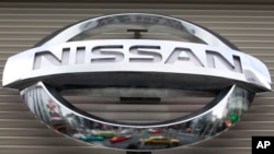 FILE - Vehicles are reflected on the logo of the Nissan Motors Co. at a showroom in Tokyo's Ginza shopping district, Japan.