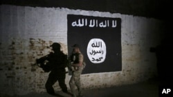 FILE - An Iraqi soldier inspects a former train tunnel displaying the Islamic State group flag, in western Mosul, Iraq, March 1, 2017. The tunnel once served as a training camp for IS fighters.