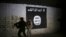 FILE - An Iraqi soldier inspects a former train tunnel displaying the the Islamic State group flag, in western Mosul, Iraq, March 1, 2017. The tunnel once served as a training camp for IS fighters.