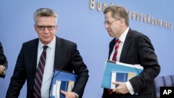 German Interior Minister Thomas de Maiziere, left, and Hans-George Maassen, head of Germany's domestic intelligence agency BfV, leave after a press conference in Berlin, July 4, 2017.