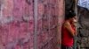 A woman covers her mouth as she stands outside her home while city workers fumigate to combat the Aedes Aegypti mosquitoes that transmit the Zika virus, at the San Judas Community in San Salvador, El Salvador, Jan. 26, 2016. 