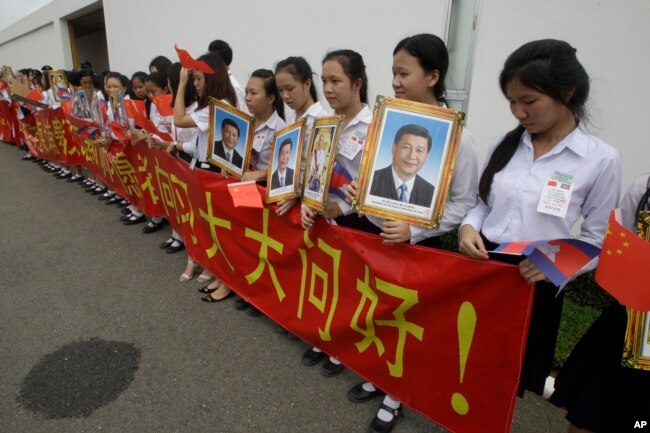 File photo - Cambodian students holding a welcome banner and photos of Chinese President Xi Jinping at Phnom Penh International Airport in Phnom Penh, Cambodia, Thursday, Oct. 13, 2016.
