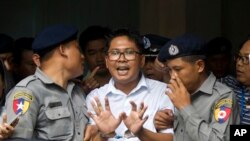 Reuters journalist Wa Lone, center, talks to journalists as he is escorted by police to leave a court in Yangon, Myanmar, Sept. 3, 2018.