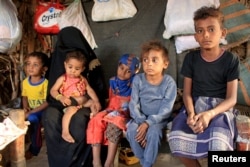 Malnourished boy Hassan Merzam Muhammad sits with his mother and brothers and sisters inside their hut in Abs district of Hajjah province, Yemen November 20, 2020. (REUTERS/Eissa Alragehi)