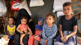 Malnourished boy Hassan Merzam Muhammad sits with his mother and brothers and sisters inside their hut in Abs district of Hajjah province, Yemen November 20, 2020. (REUTERS/Eissa Alragehi)