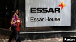 FILE - Employees walk past an Essar Group logo outside their headquarters in Mumbai May 20, 2013. 