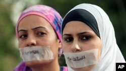 Jordanian journalists protest in front the Jordanian House of Parliament, with their mouths covered with tape and the words "article 23," in Arabic, against proposed changes to the anti-corruption law they believe will muzzle press freedoms, Amman, Septem
