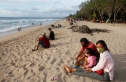 Para wisatawan lokal mengenakan masker saat menikmati suasana pantai di Bali, di tengah pandemi Covid-19, Selasa, 22 Desember 2020.