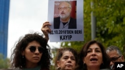 Activists, members of the Human Rights Association Istanbul branch, holding posters with photos of missing Saudi journalist Jamal Khashoggi, talk to members of the media, during a protest in support of him near the Saudi Arabia consulate in Istanbul, Oct. 9, 2018.