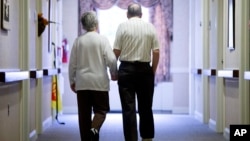 FILE - An elderly couple walks down a hall in Easton, Pennsylvania, Nov. 6, 2015. 